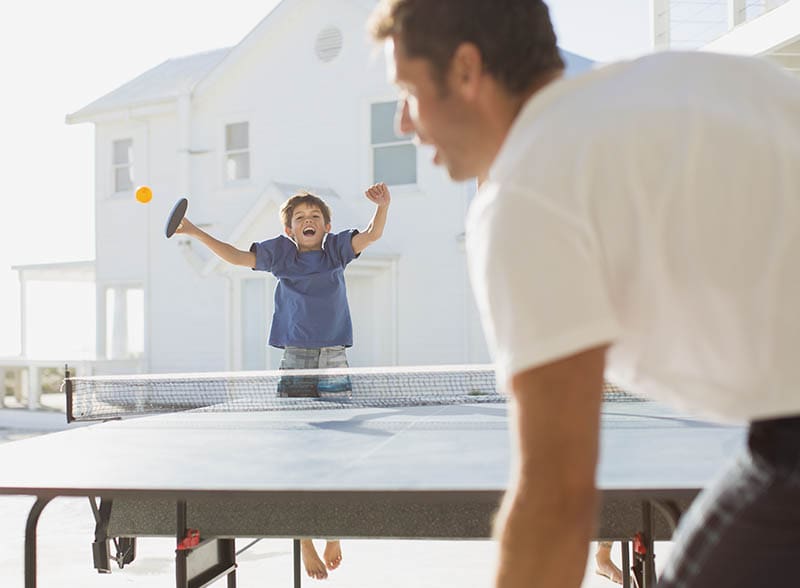 Father and son playing table tennis outdoors